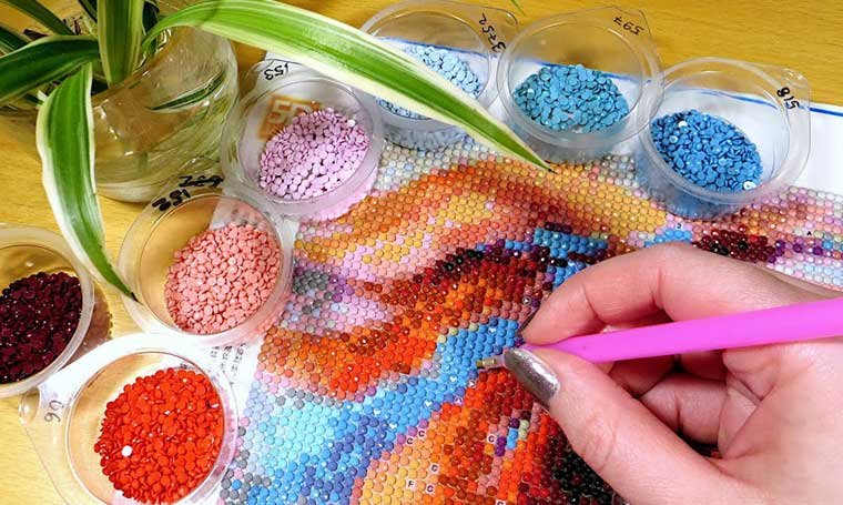 A women hand explore Benefits of Diamond Painting different color's with pincial